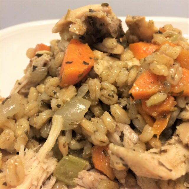 chicken and barley with carrots and onions on white plate