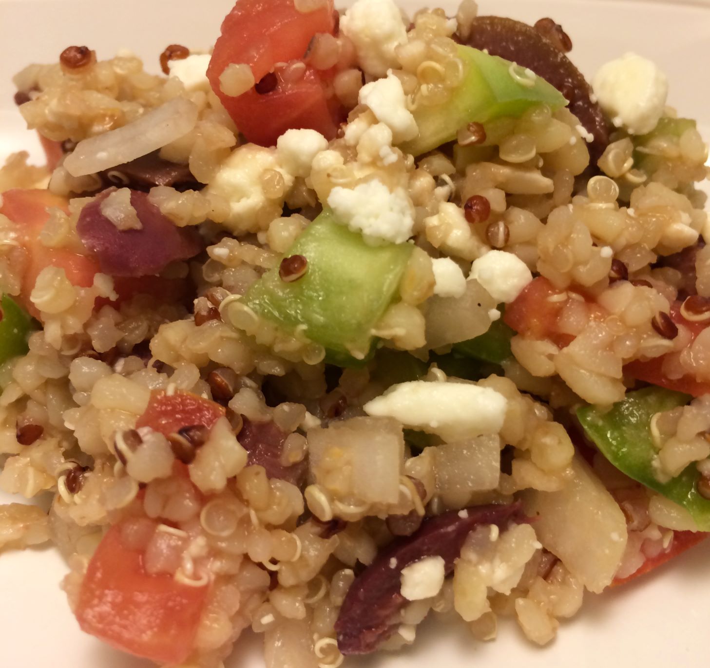 greek quinoa salad scooped onto white plate