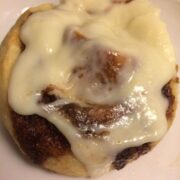 single cinnamon roll with frosting on white plate