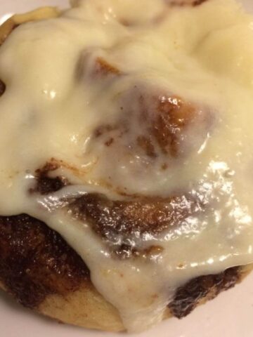 single cinnamon roll with frosting on white plate
