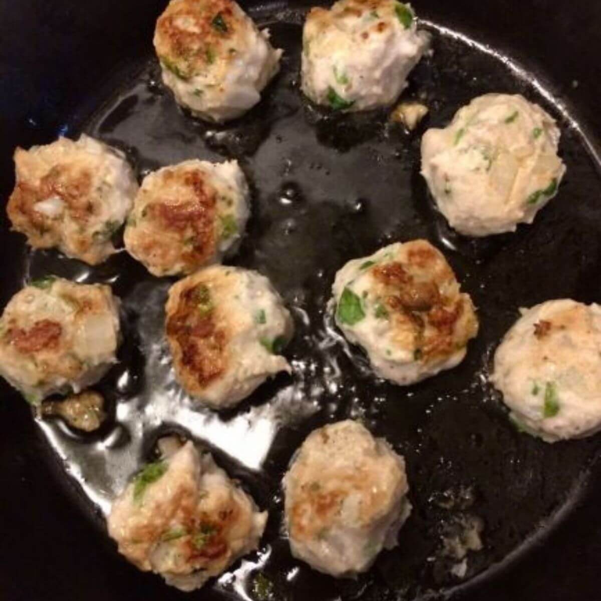 meatballs flipped to show cooked side in cast iron