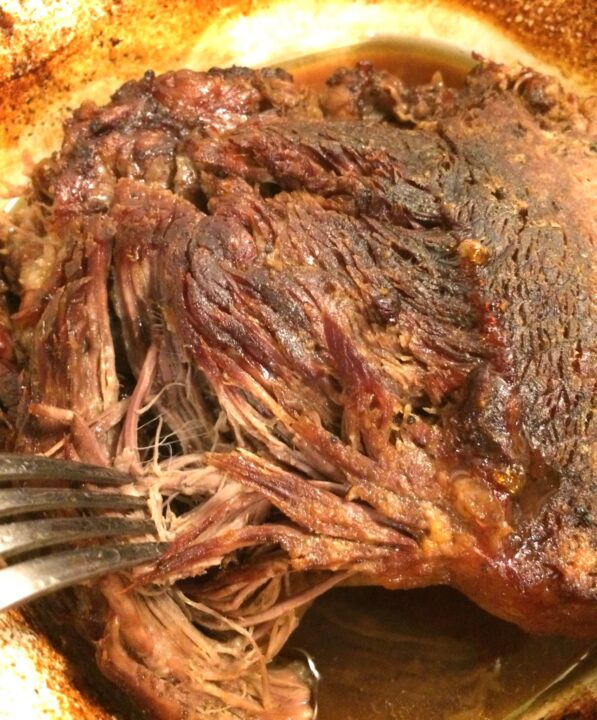 close up of beef roast being shredded with a fork
