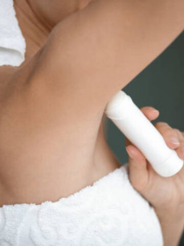 woman applying deodorant with white towel
