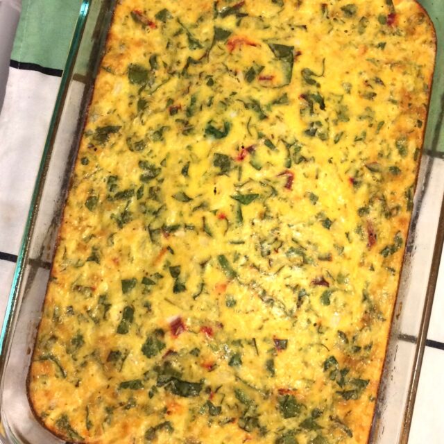 breakfast casserole in glass pan on green and white towel