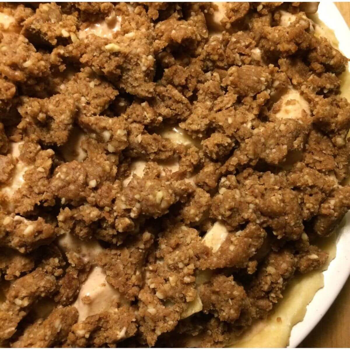 close up view of crumble topping on top of apple pie filling