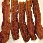 baked bacon lined in a row on a white plate