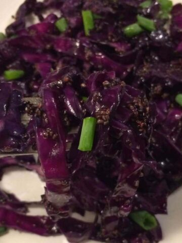 stir fried cabbage with chia with fork lifting small portion all on white plate