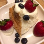 dessert cream topping on a slice of angel food cake with strawberries and blueberries dipped in cream
