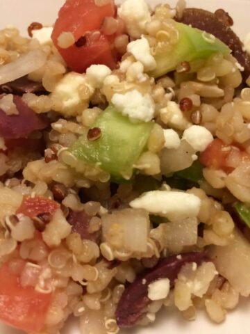 greek quinoa salad scooped onto white plate
