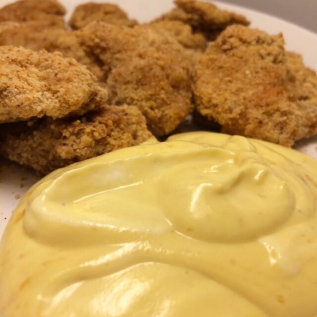 honey mustard sauce in foreground with homemade chicken nuggets in background