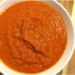 marinara sauce in a white bowl on wooden cutting board