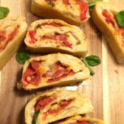 pepperoni pizza bread in slices with fresh basil on wood cutting board