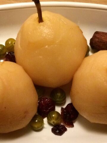 poached pears with berries on white plate