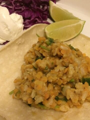 lentils and rice on soft corn tortillas with lime slices, purple cabbage, greek yogurt
