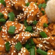 sesame chicken with sesame seeds and diced green onion on top