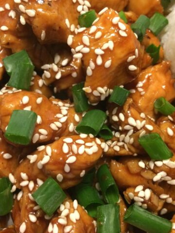 sesame chicken with sesame seeds and diced green onion on top