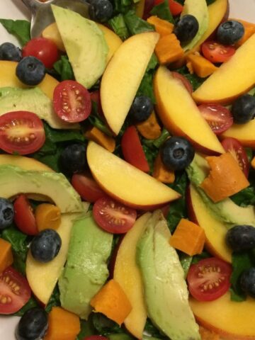 spinach salad with avocado, sweet potato, blueberries, cherry tomatoes, nectarine