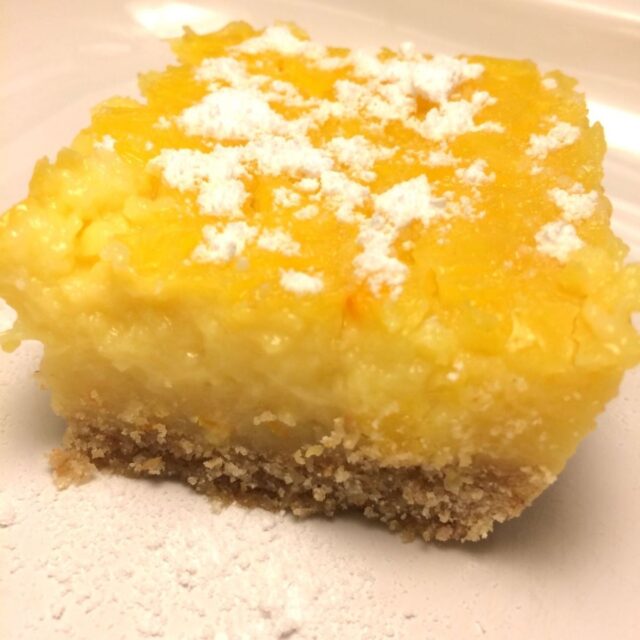 lemon bar on white plate with powdered sugar on top