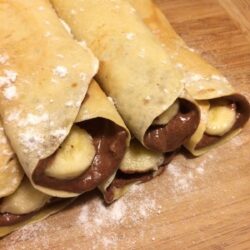 chocolate honey banana crepes rolled and stacked with fresh banana slices in the middle