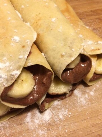 chocolate honey banana crepes rolled and stacked with fresh banana slices in the middle