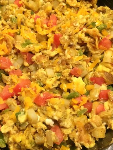 breakfast burrito skillet cooked in case iron skillet topped with shredded cheese and tomatoes