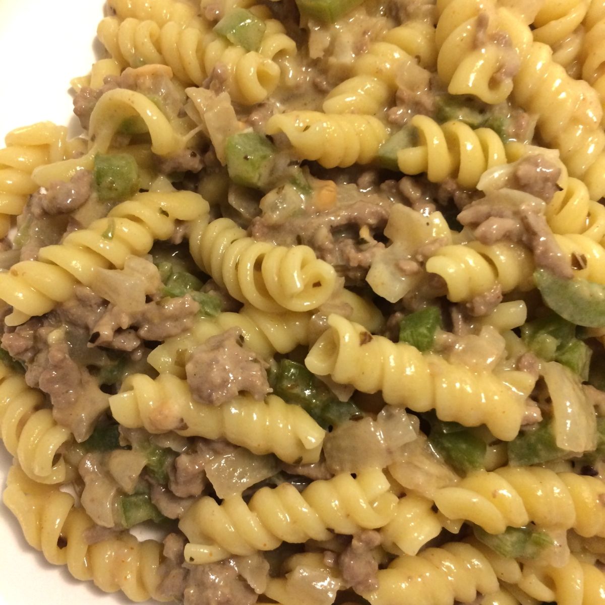 ground beef with veggies in a cream sauce with rotini pasta on a white plate