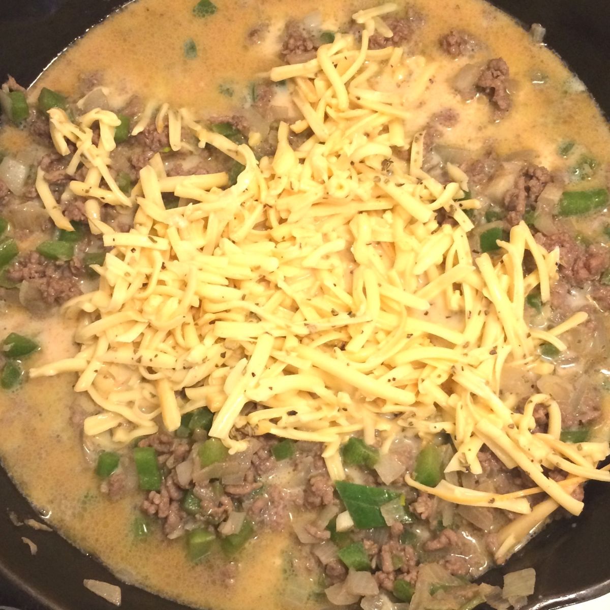 creamy beef rotini with sauce and shredded cheese in cast iron skillet