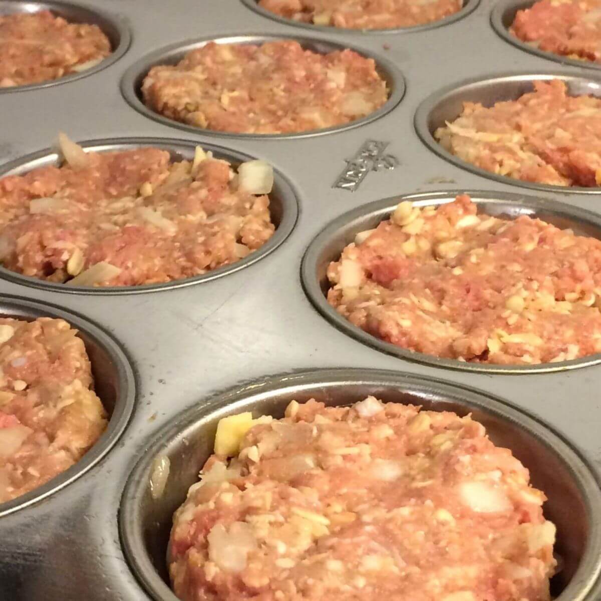 meatloaf mixture pressed into stainless steel muffin tin cups