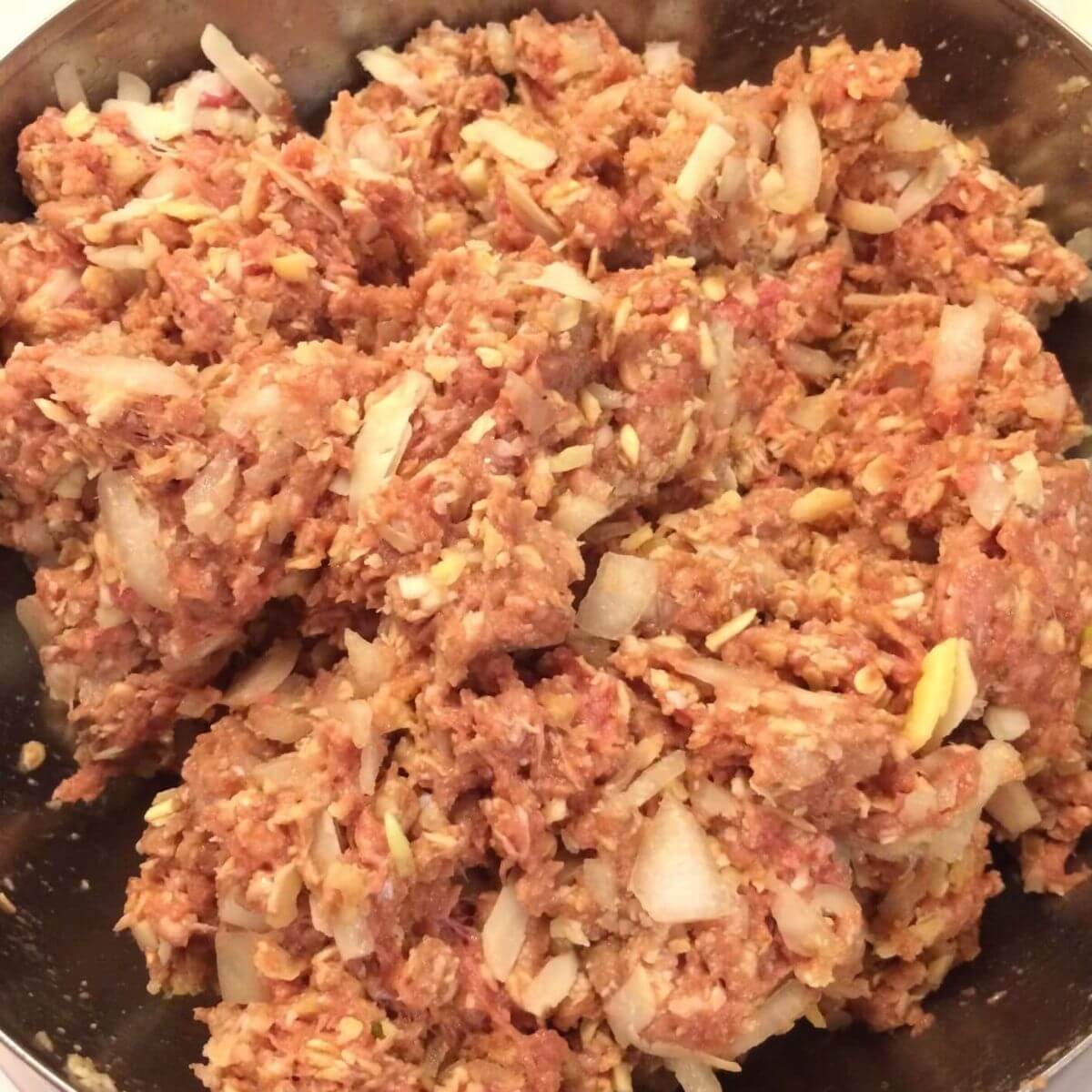 all meatloaf ingredients mixed together in stainless steel bowl