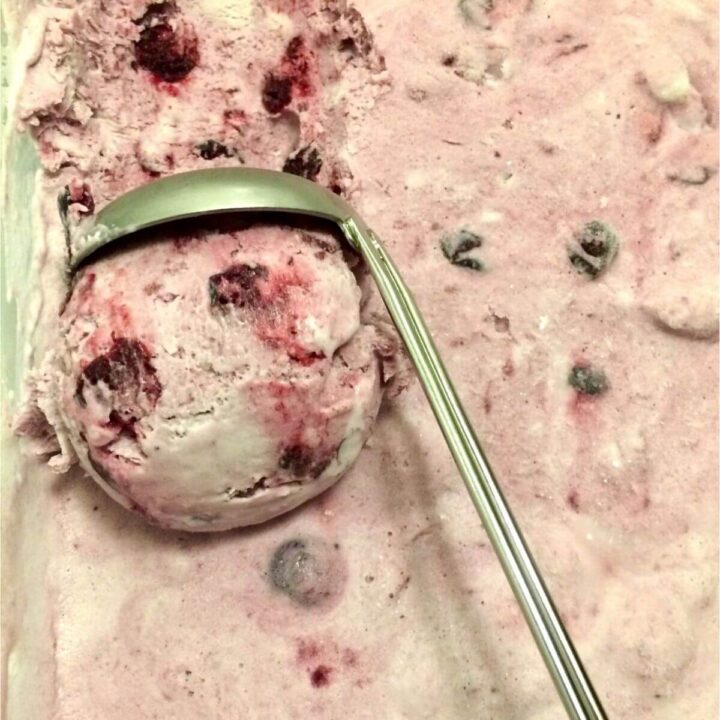 Finished frozen ice cream being scooped with silver scoop.