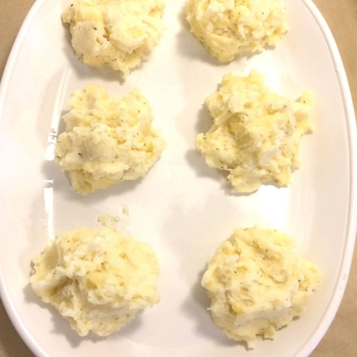 Mashed potato filling split into 6 portions on white oval plate.