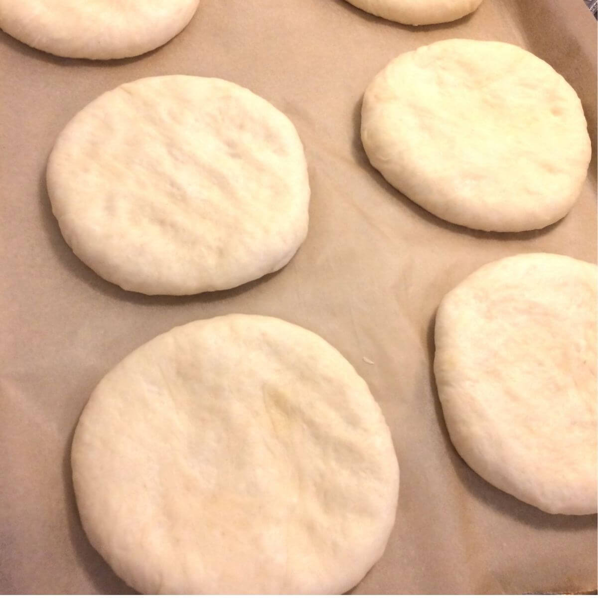 potato bread rounds pressed out flat on parchment paper, uncooked.