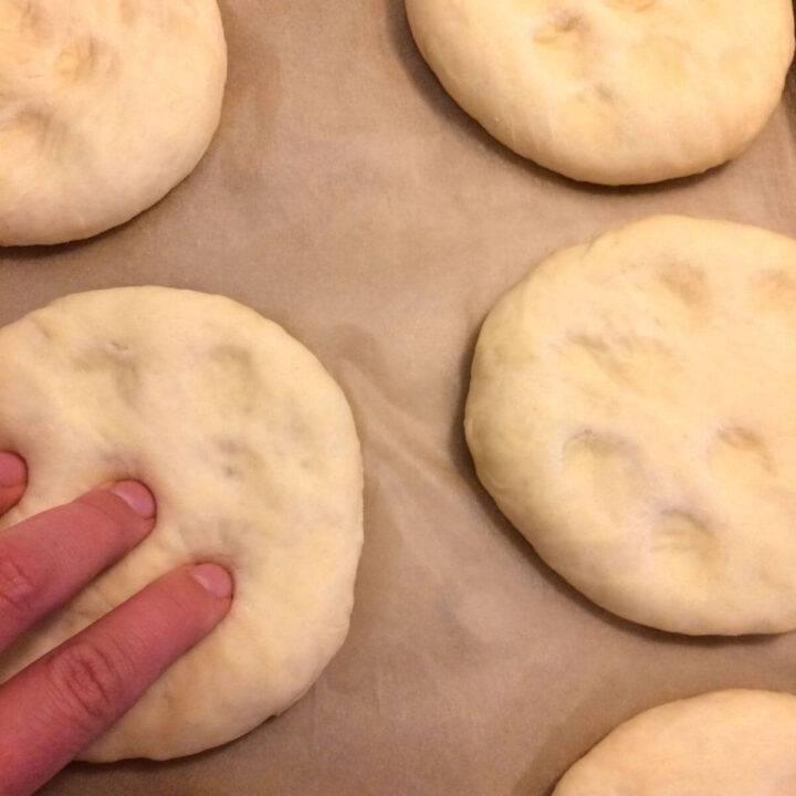 uncooked rounds with indents on tops with fingers pressing into bottom left round.