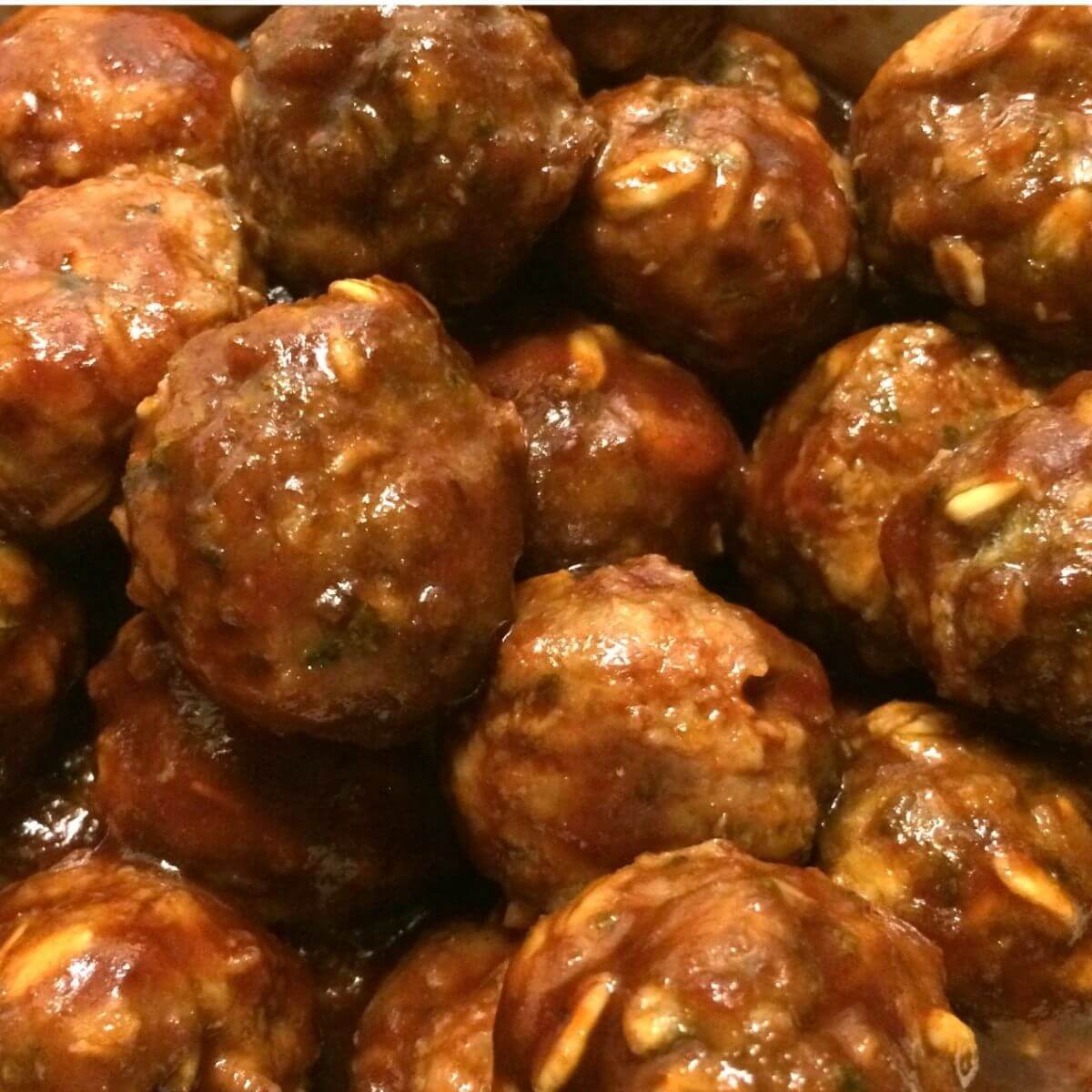 Complete cooked meatballs with barbecue sauce piled up, close up view.