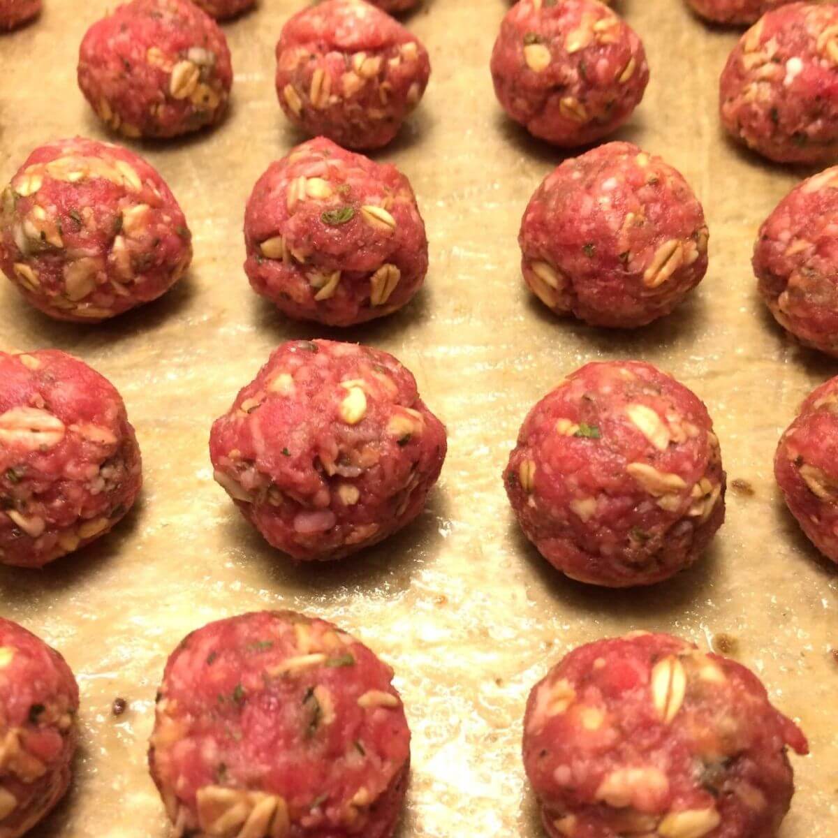 uncooked honey barbecue meatballs on cookie sheet lined up