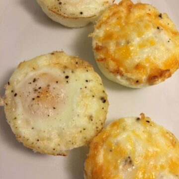 baked eggs placed on a white plate in a zig zag pattern, 2 with cheese baked on top and 2 without