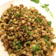 completed ground pork hash plated on an oval plate with fresh cilantro garnish and a sprig of cilantro in the upper right corner