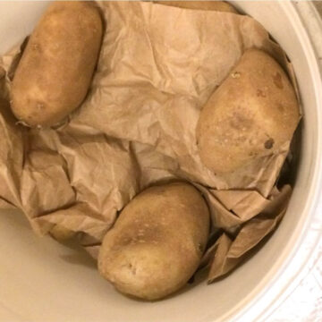 russet potatoes in a 5 gallon recycled white bucket with brown paper inside for padding