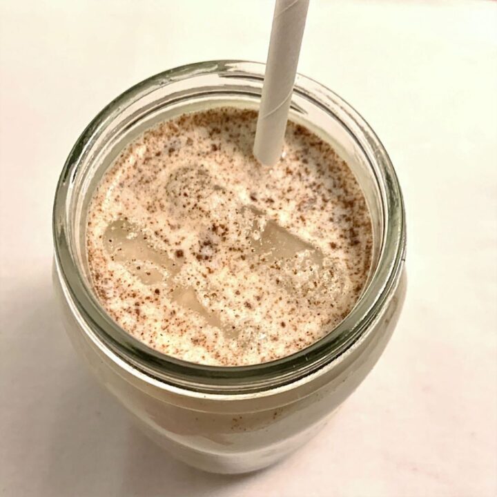 bird's eye view of horchata in a mason jar with 2 floating ice cubes and a paper straw