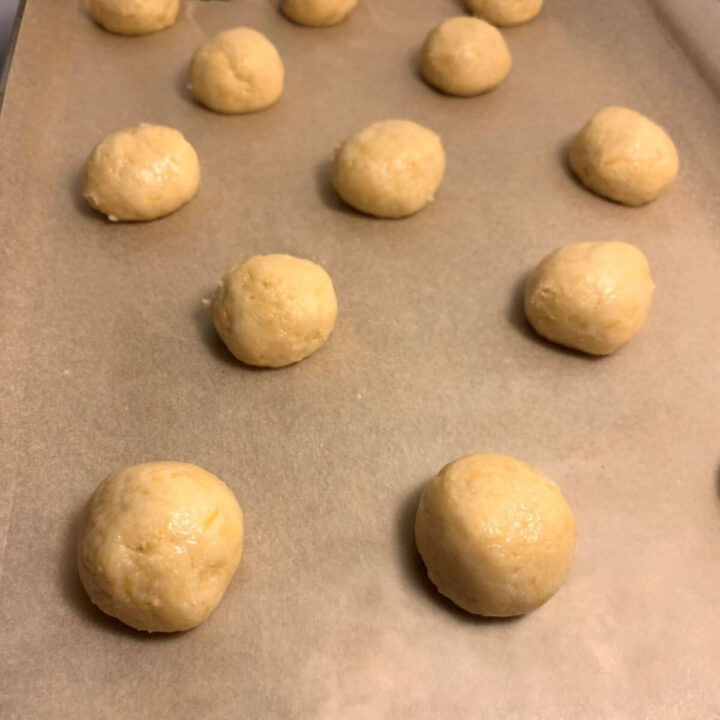 lemon cookie dough balls on parchment paper on cookie sheet