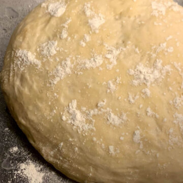 bread dough risen and dusted with flour on a cookie sheet.
