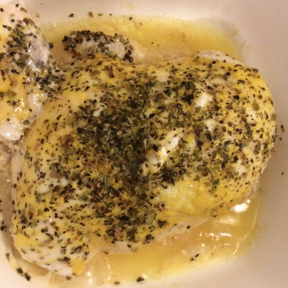 chicken in a corning ware dish with honey mustard sauce and seasonings