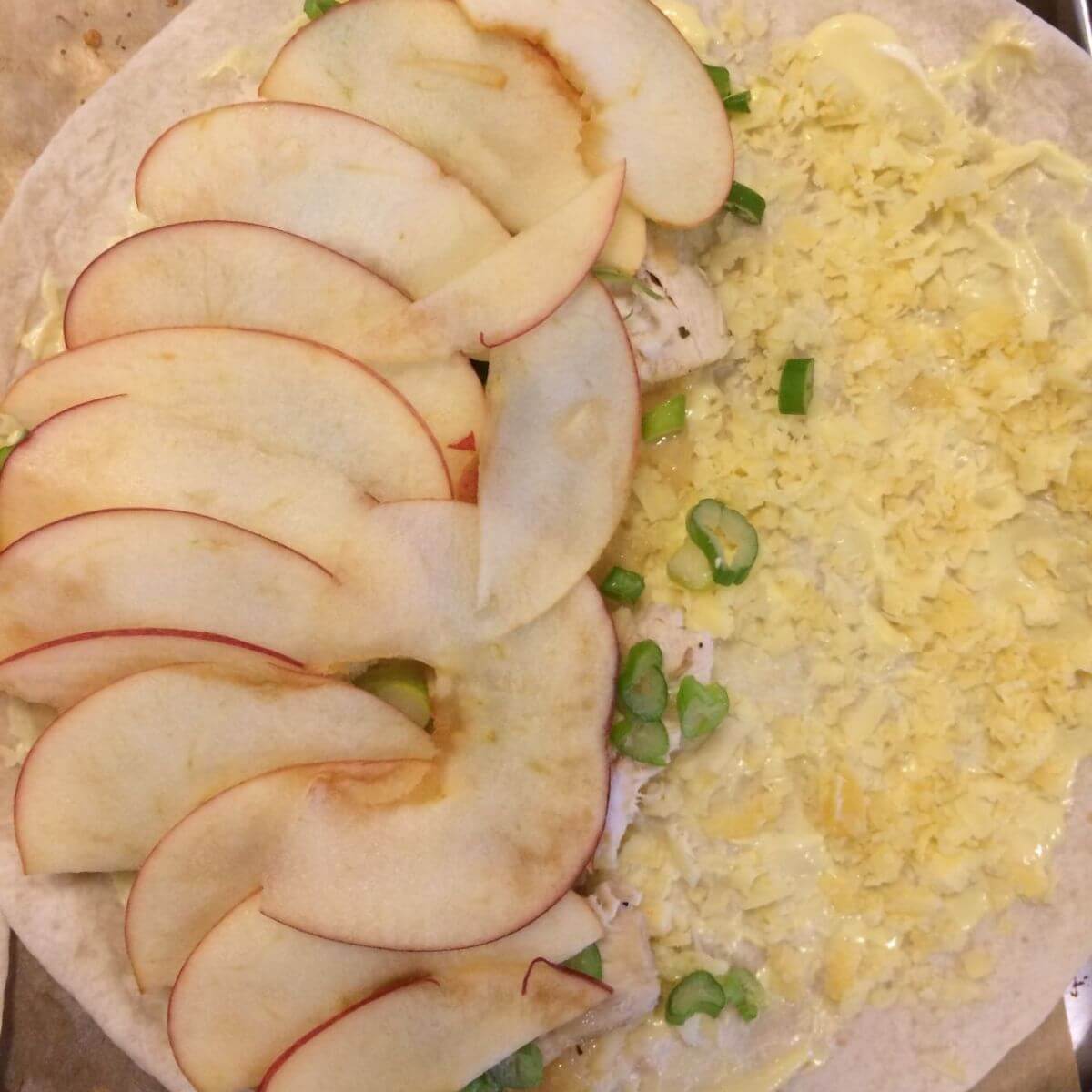 tortilla with cheese, sliced green onions, chicken, and sliced apples