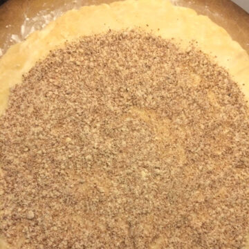 up close of almond sprinkle on base of pastry, on pizza stone.