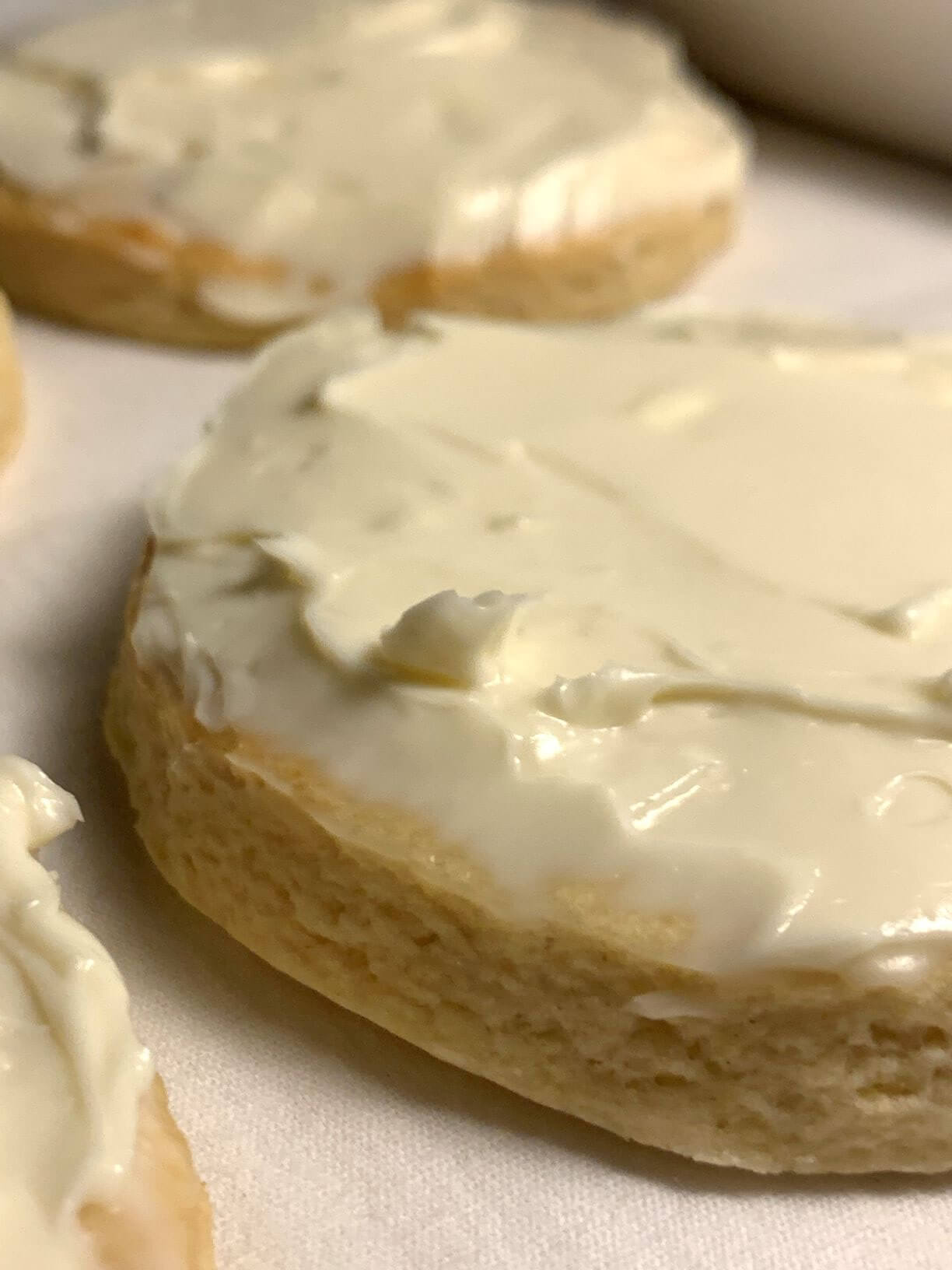 Sugar cookies with creamy frosting on a white towel, close up.