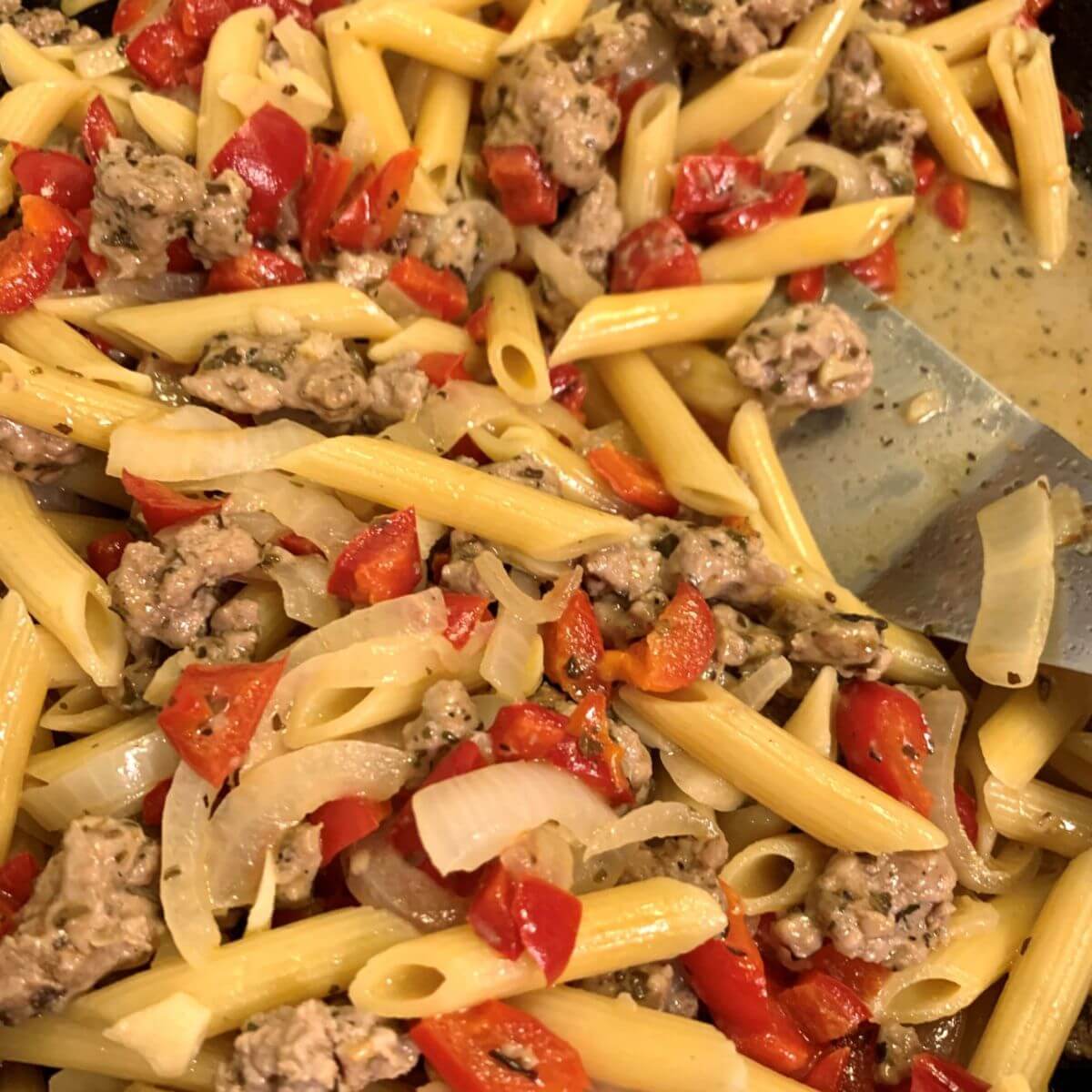 Penne pasta with ground pork, red peppers, and onion in a light sauce.