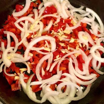 sliced onion, red bell pepper, diced garlic in a cast iron skillet