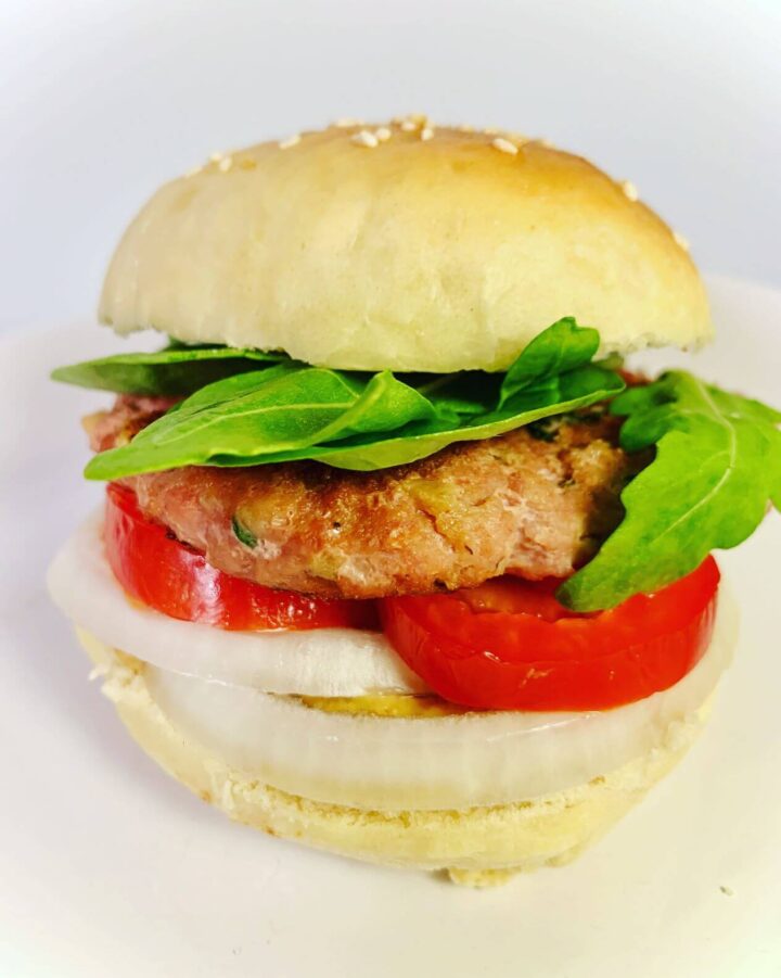 turkey burger with homemade buns with sesame seeds, mixed lettuce blend, sliced tomato, sliced onion, mustard, and turkey patty.