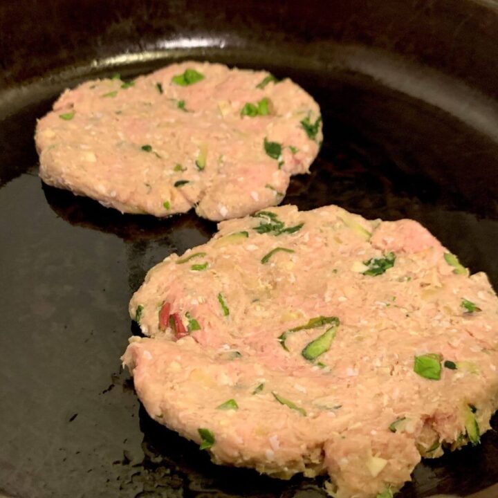 2 turkey burger patties uncooked on cast iron skillet.i