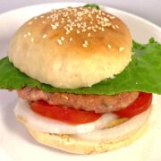 Square image of turkey burger with homemade buns with sesame seeds, mixed lettuce blend, sliced tomato, sliced onion, mustard, and turkey patty.